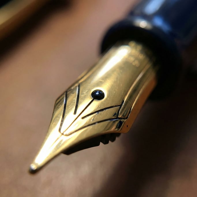 Gold-plated and iridium-tipped, a fountain pen nib fills the frame