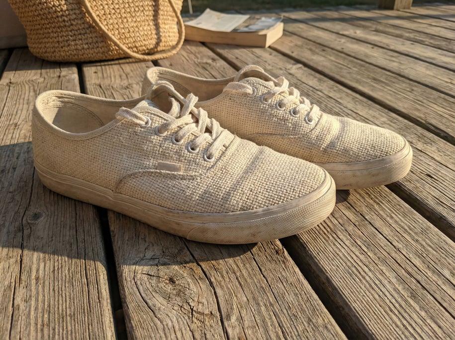 A pair of canvas sneakers placed casually on sun-bleached wooden decking