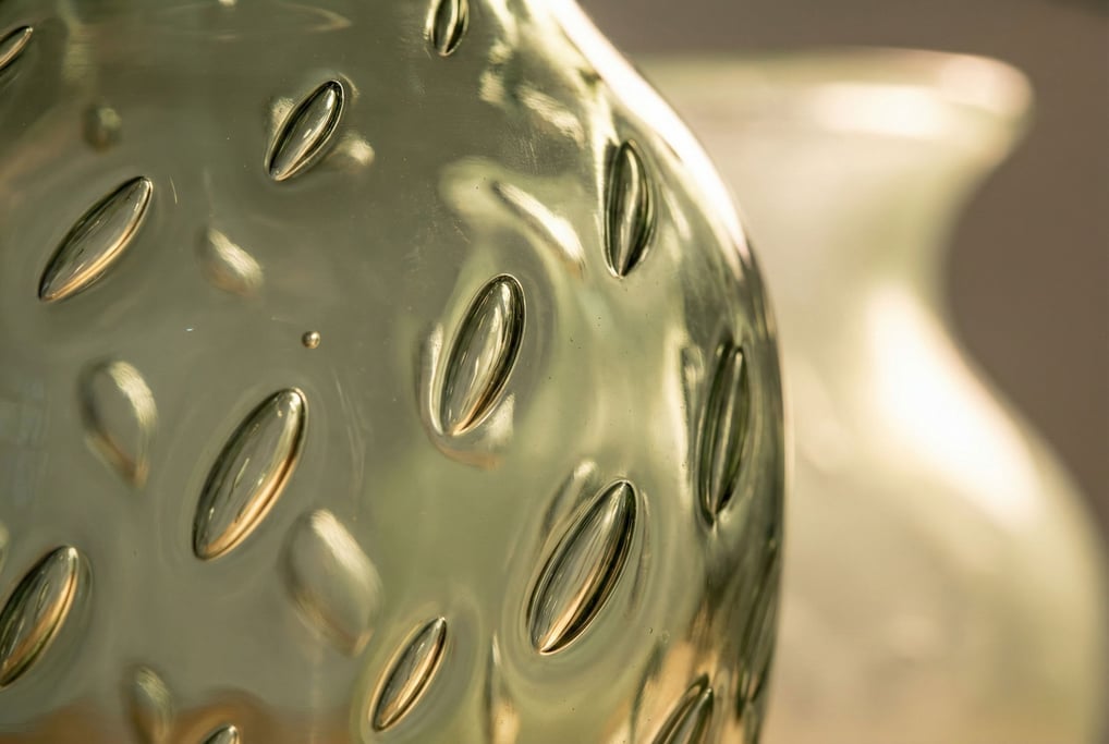 Macro shot of a hand-blown glass vase wall showing trapped air bubbles of various sizes frozen in the molten glass