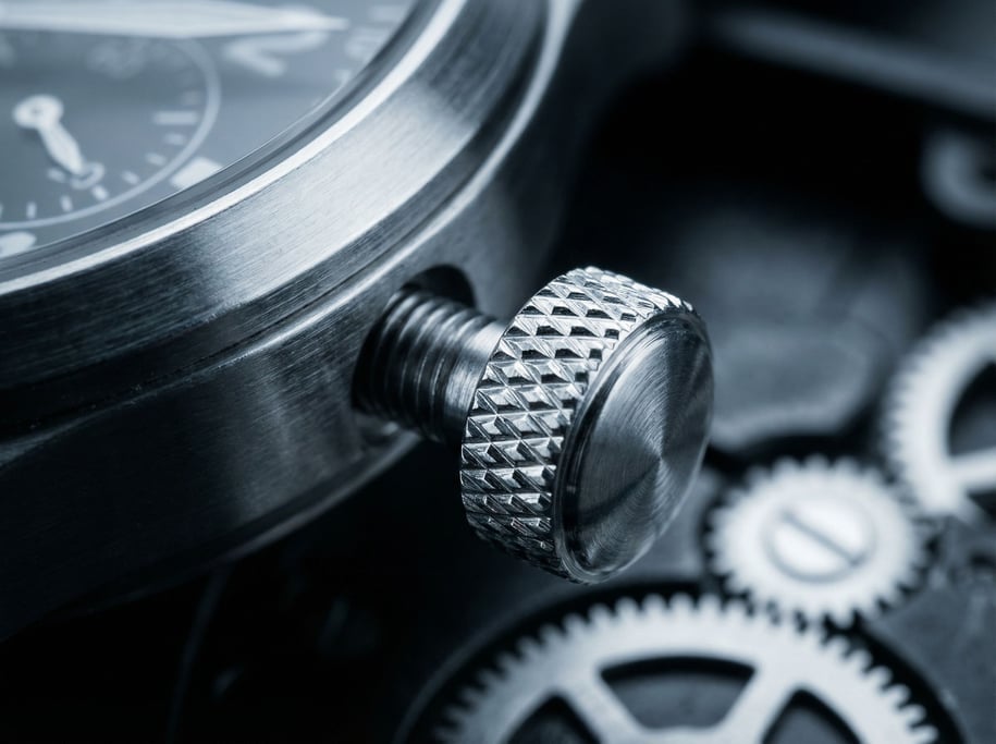 Extreme close-up of a watch crown and its knurled edge showing the precision machining pattern of tiny diamond-shaped indentations