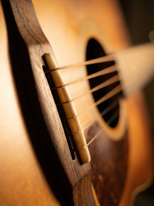 Extreme close-up of a wooden guitar bridge showing the bone saddle seated in its slot