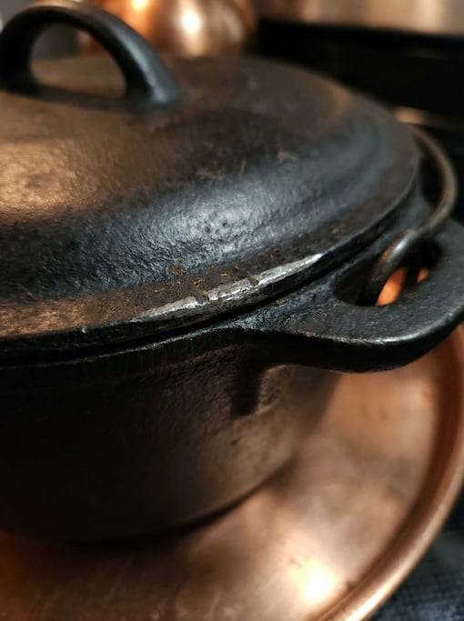 Extreme close-up of the rim of a cast iron Dutch oven where the lid meets the body