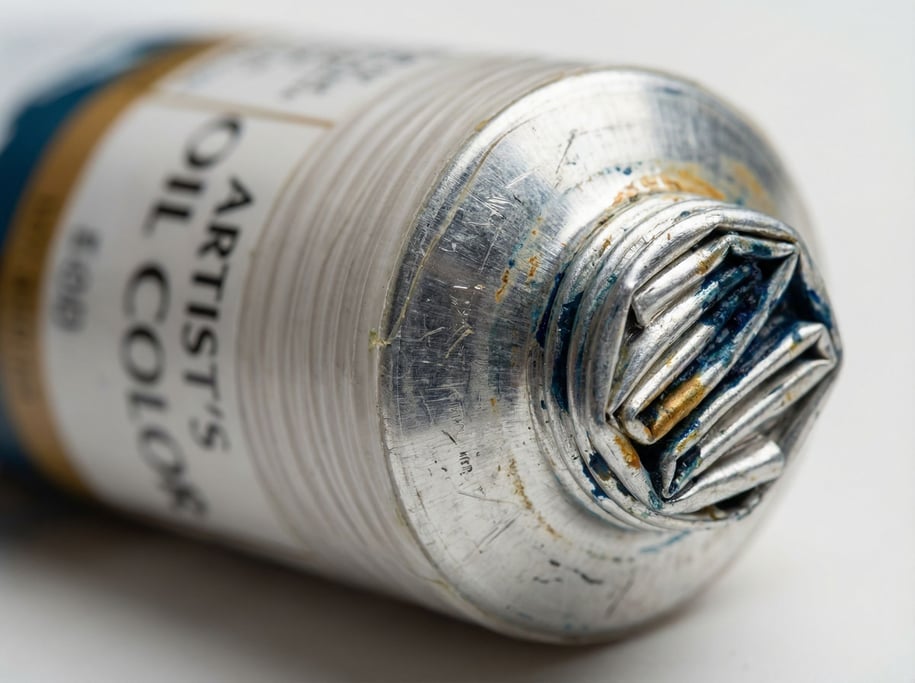 Extreme close-up of a paint tube crimp showing the folded aluminum end where the tube was sealed during filling