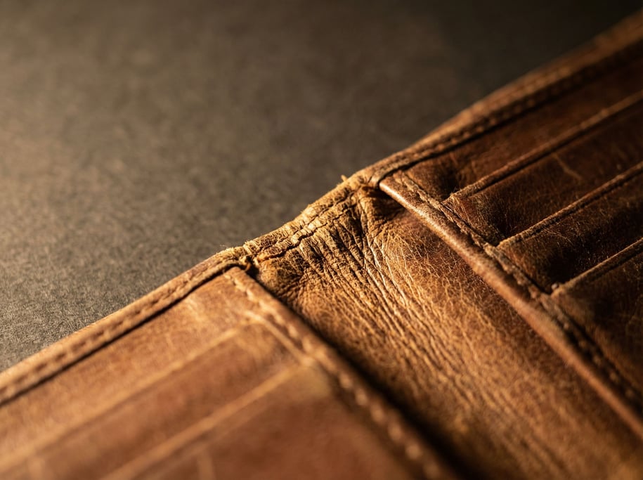 Extreme close-up of a leather wallet bifold hinge where the two halves of leather meet