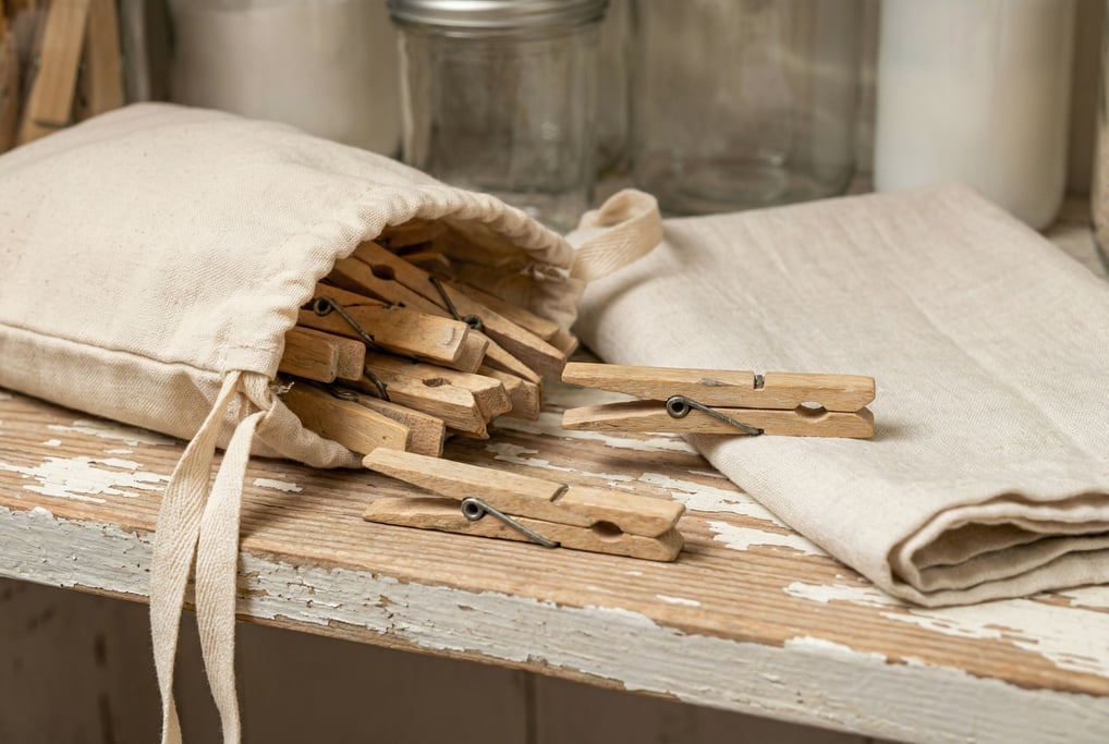 A handful of wooden clothespins in a canvas drawstring bag on a laundry room shelf