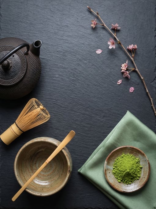 Overhead arrangement of Japanese tea ceremony items on a dark slate surface
