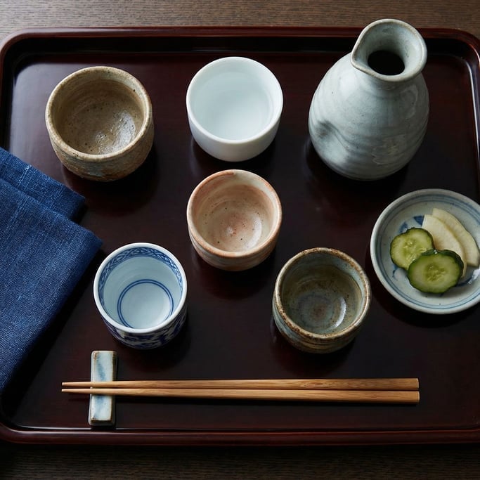 Flat-lay arrangement of a sake tasting set on a dark lacquered tray