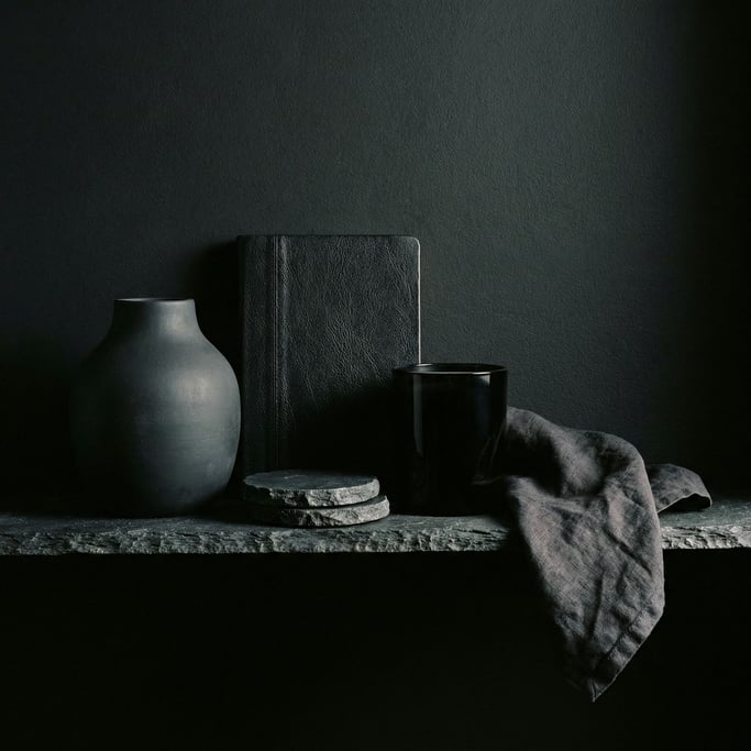 Five objects in pure black — a ceramic vase with a matte chalky surface