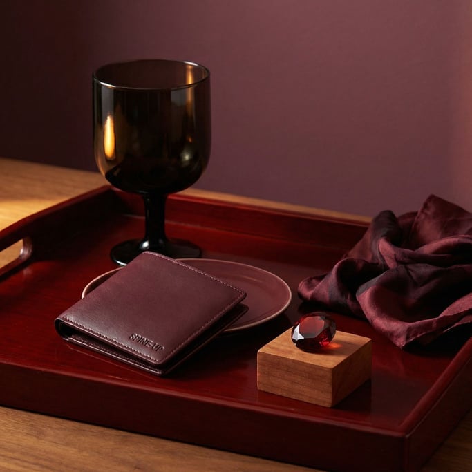 Gathered on a deep red lacquered tray: dark wine glass catching a single highlight