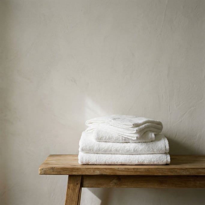 A stack of white cotton towels on a teak bench, spa-like simplicity, neutral tones (n3fpnyhi)