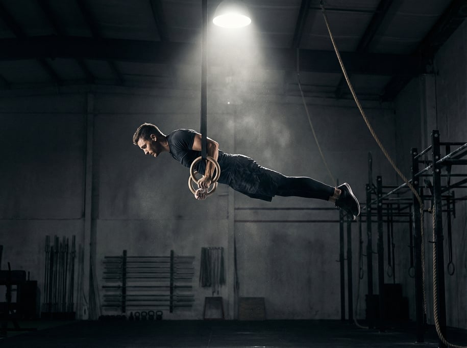Male athlete at the top of a muscle-up on gymnastics rings, body fully extended