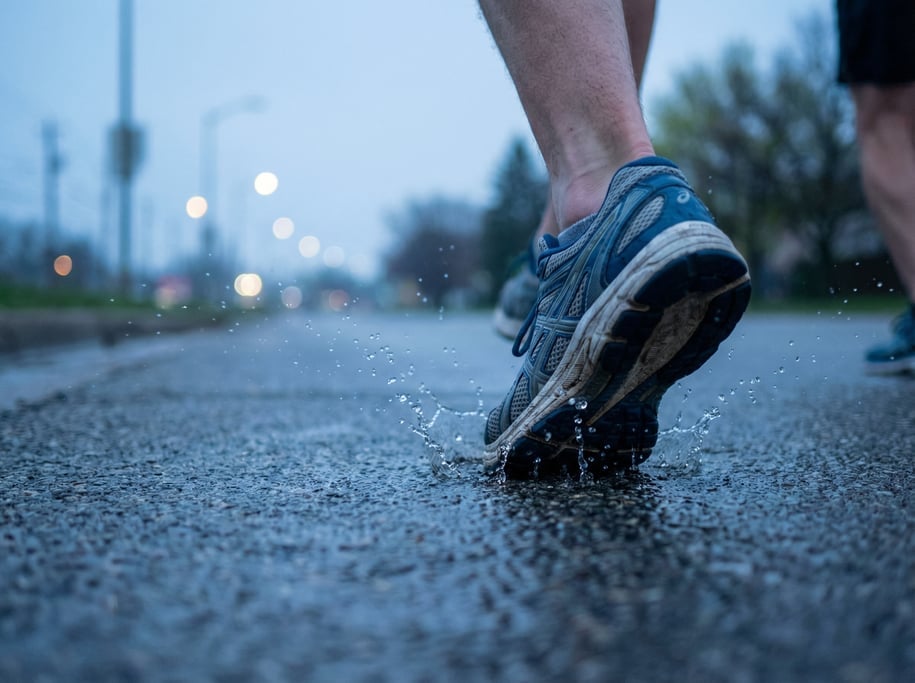 Close-up of running shoes hitting wet pavement mid-stride