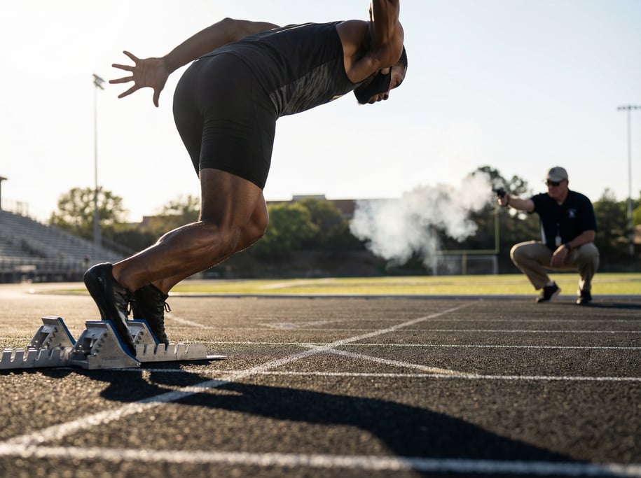 Sprinter exploding out of starting blocks on a track, dramatic low angle, muscles tensed