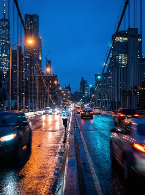 Urban runner crossing a rain-slicked city bridge at blue hour