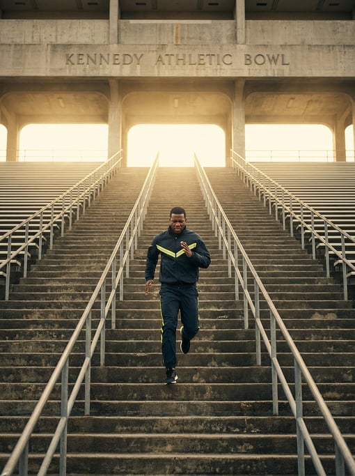 Staircase runner sprinting up concrete stadium steps, shot from below looking up