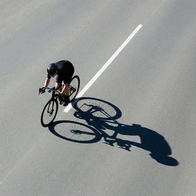 Overhead shot of a cyclist from directly above on a smooth grey asphalt road with white lane marking