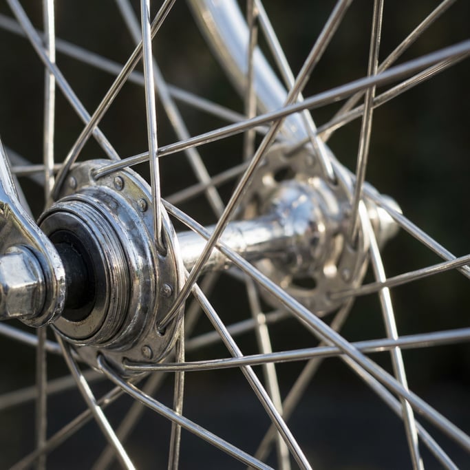 Close-up of a bicycle wheel hub and spokes, chrome components catching light