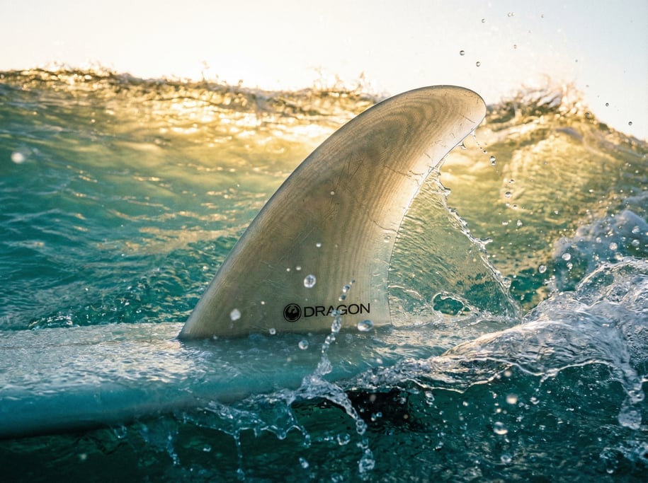 Close-up of a surfboard fin cutting through a turquoise wave face