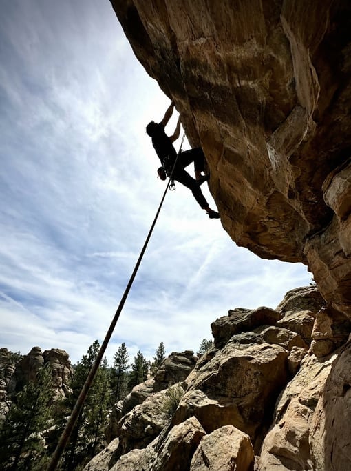 Rock climber on an overhang route at an outdoor crag, shot from below