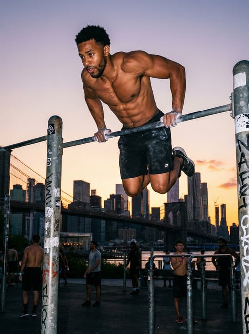 Athlete doing muscle-ups on a set of outdoor pull-up bars in an urban calisthenics park