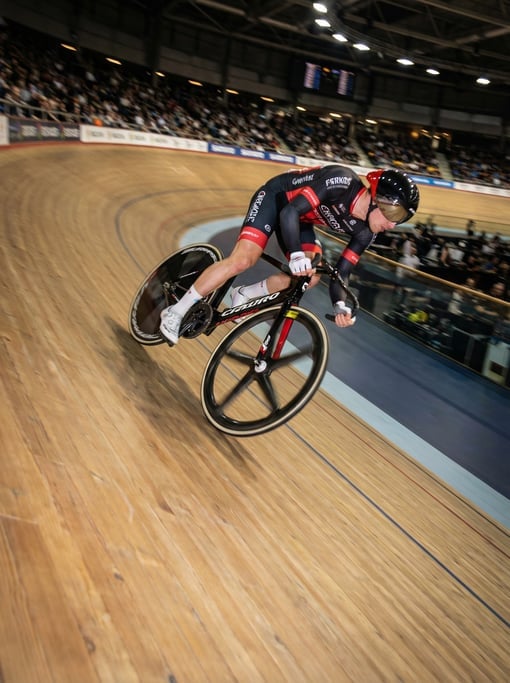Track cyclist on a velodrome banking, extreme lean angle, shot from inside the track