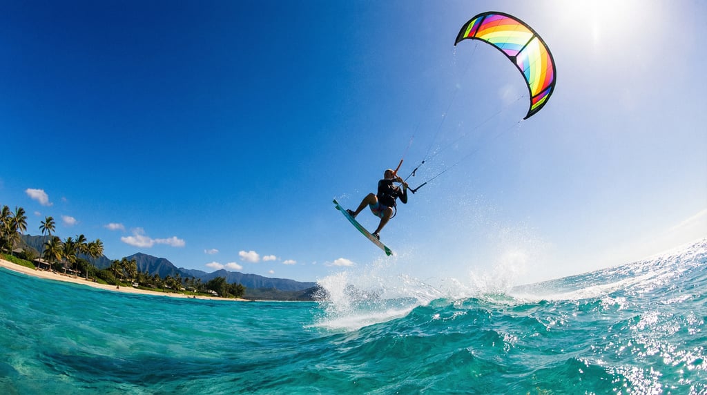 Wide shot of a kitesurfer launching off a wave, colorful kite against blue sky