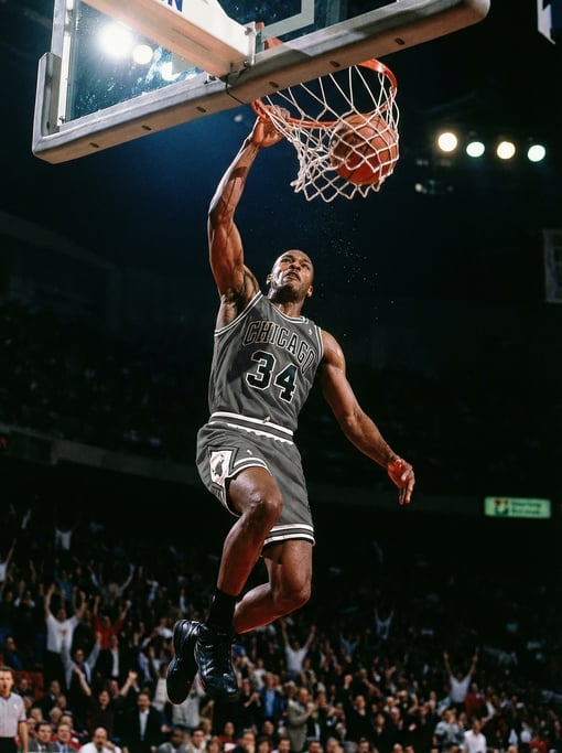 Basketball player going up for a slam dunk, one hand on the ball above the rim