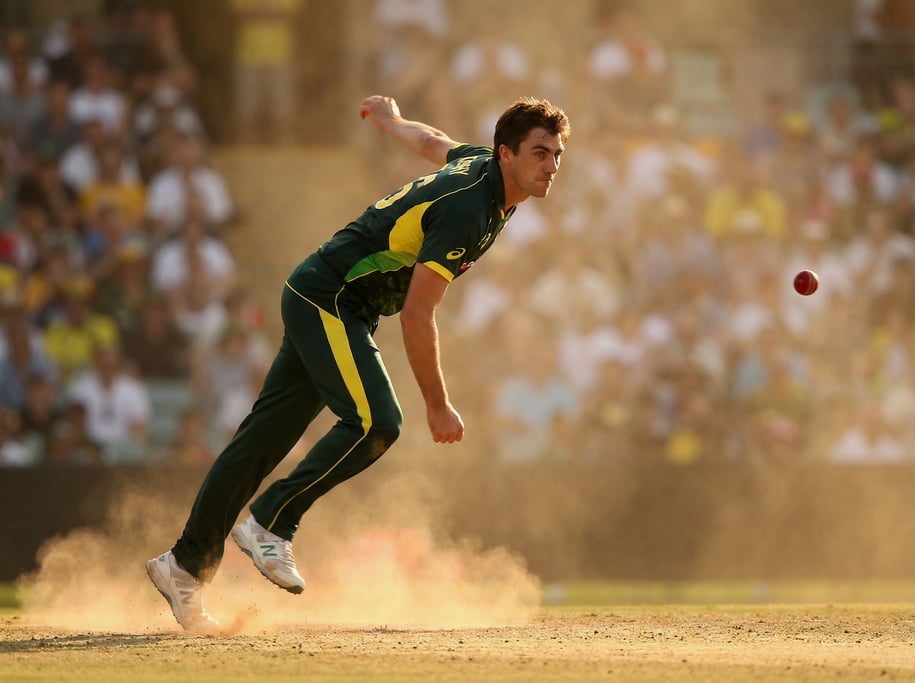 Cricket bowler in the delivery stride, arm coming over at pace, the ball just leaving the hand