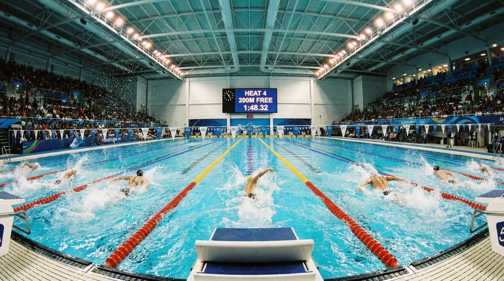 Wide shot of a competitive swimming pool from the timing end, eight lanes with swimmers mid-race