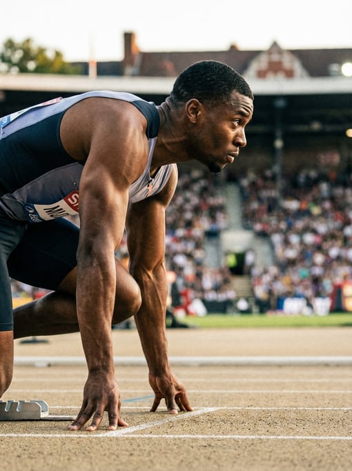Sprinter in the set position in the blocks, fingers on the track surface