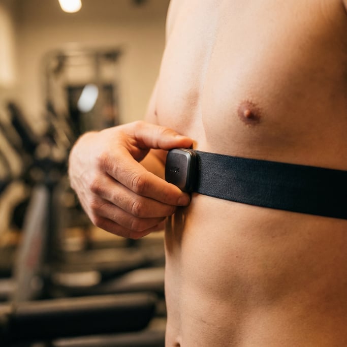 Close-up of a heart rate monitor chest strap being adjusted, the sensor pad visible against skin