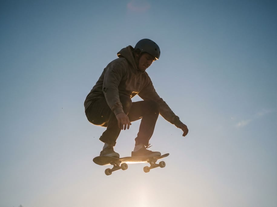 A skateboarder mid-trick, frozen in air, low-angle shot against an open sky