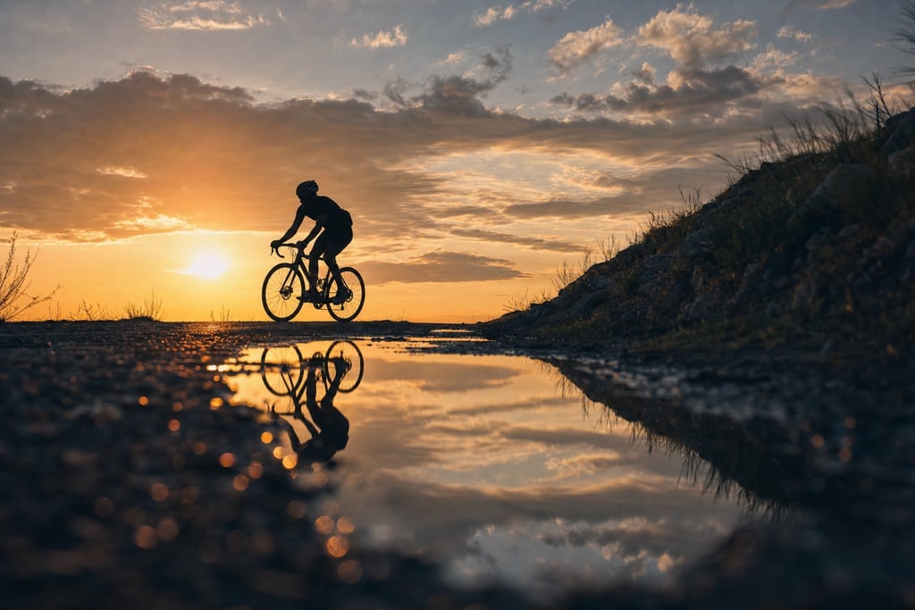 Silhouette of a cyclist against a sunset sky streaked with dramatic clouds