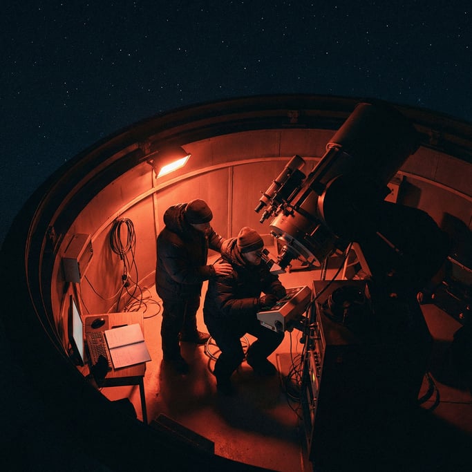 An astronomer at a telescope in a mountaintop observatory, red light preserving night vision