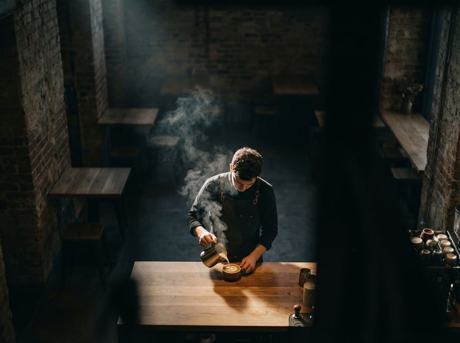 A barista pouring latte art, shot from above, steam and swirl patterns in the milk (i4wmux9)