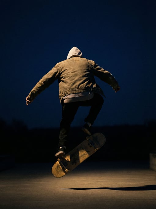 A skateboarder mid-trick, frozen in air, low-angle shot against an open sky (wrmkj7c8)