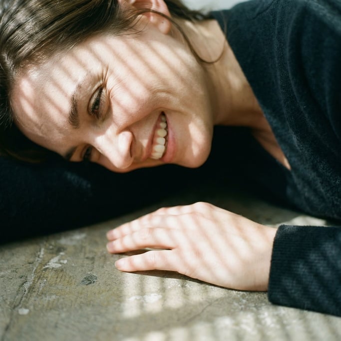 A woman meditating alone in an empty loft, cross-legged on bare concrete, single window light (ma3hp64x)
