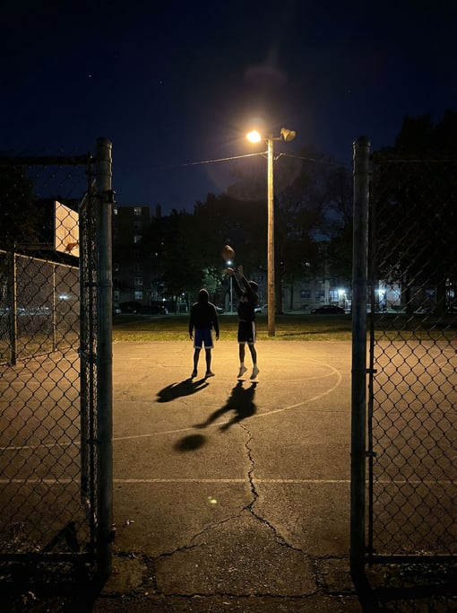 A nighttime basketball court in an urban park