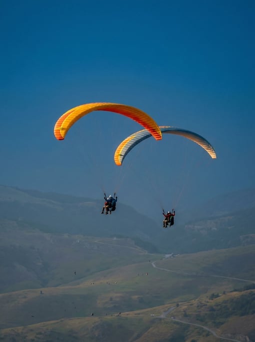 Two paragliders tandem-flying high above a valley
