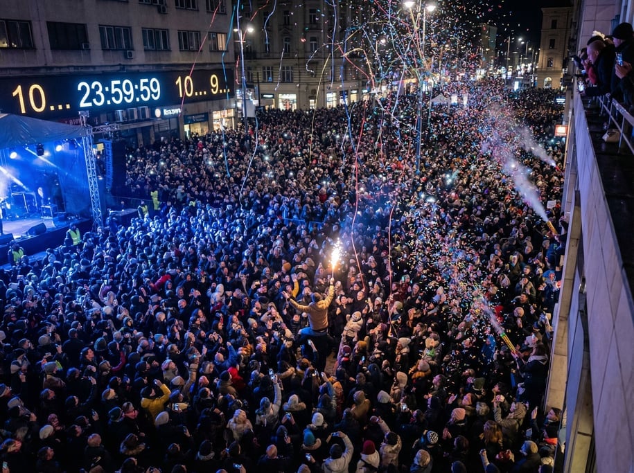 A massive crowd at a New Year countdown event in a city square