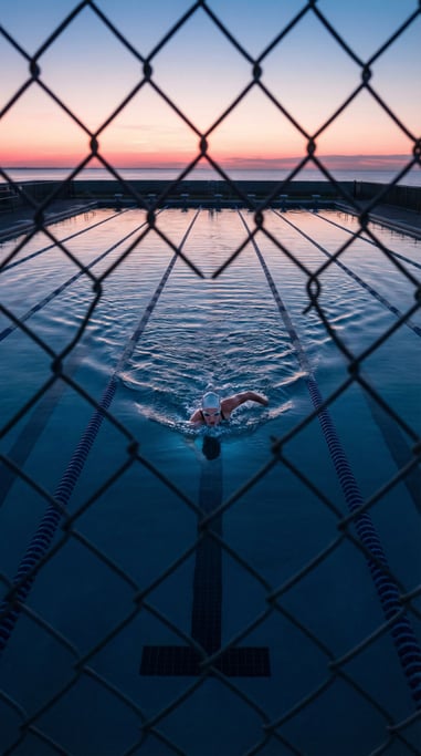 A woman in her 30s doing laps in an outdoor pool at dawn