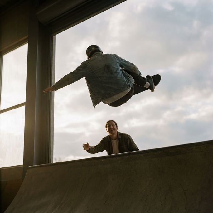 A skateboarder mid-trick, frozen in air, low-angle shot against an open sky (k3fwjjxb)