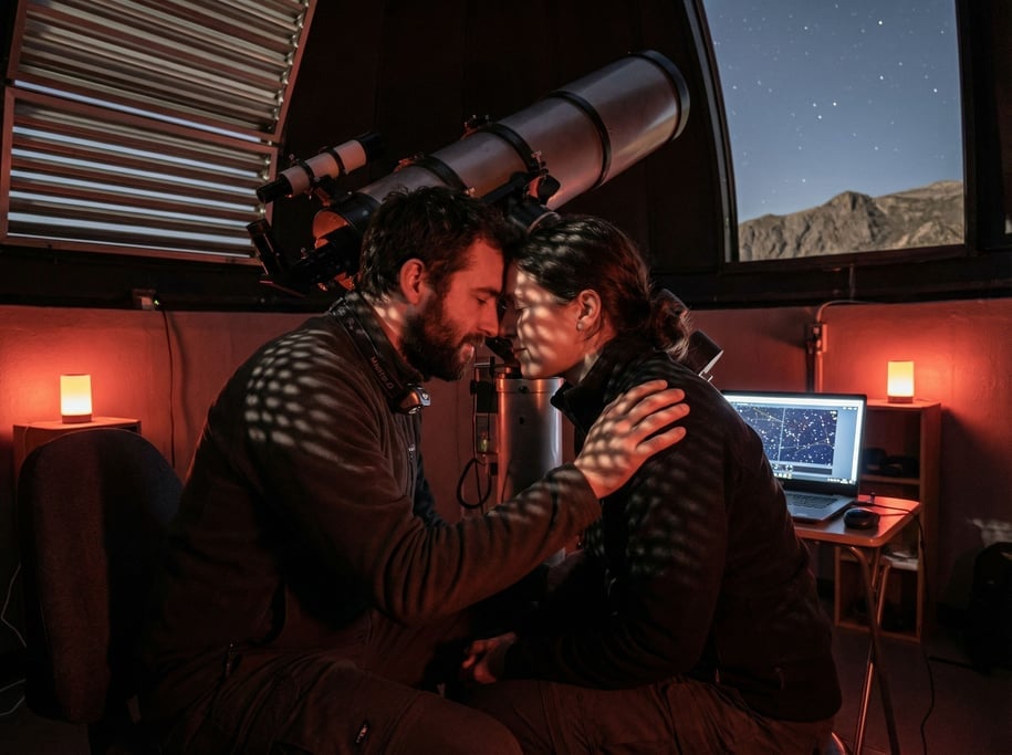 An astronomer at a telescope in a mountaintop observatory, red light preserving night vision (3n8dyyh)