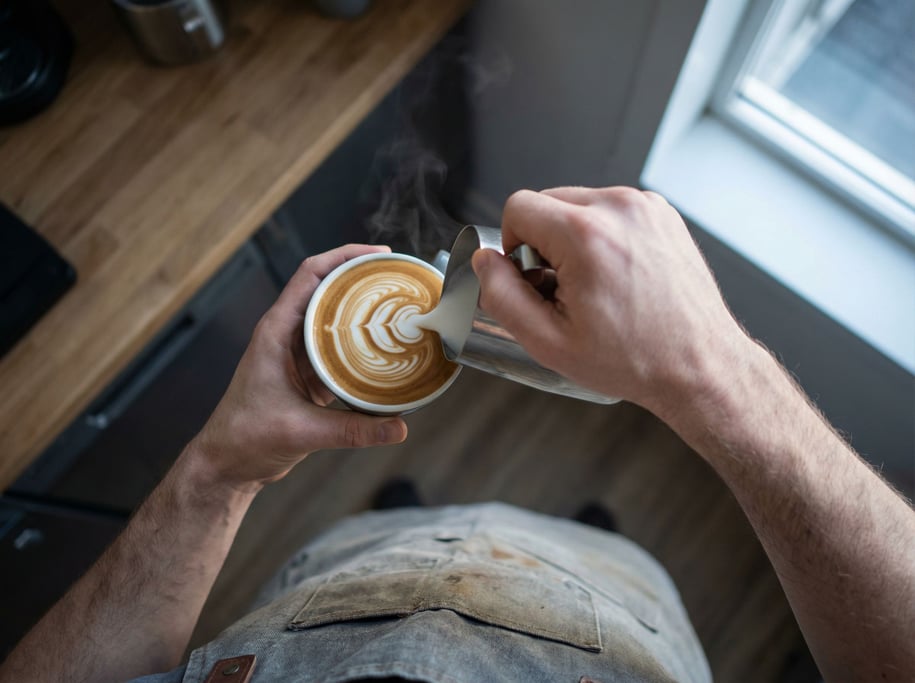 A barista pouring latte art, shot from above, steam and swirl patterns in the milk (saxywum4)