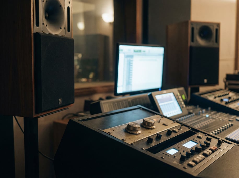 A pair of studio monitor speakers flanking a mixing desk, volume knobs in sharp focus
