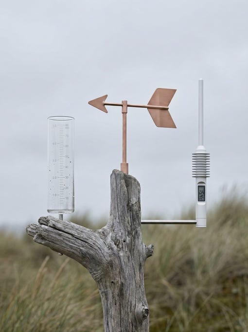 A concept home weather station with three separate sensor modules — a rain gauge in clear borosilicate glass