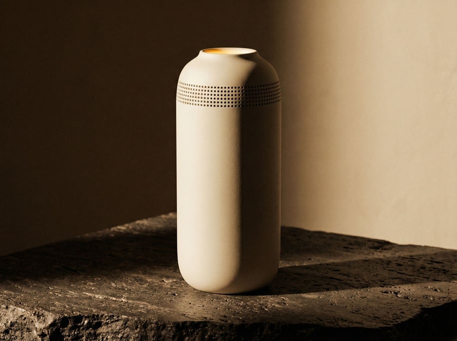 A standalone voice assistant shaped like a tall narrow matte cream polycarbonate cylinder