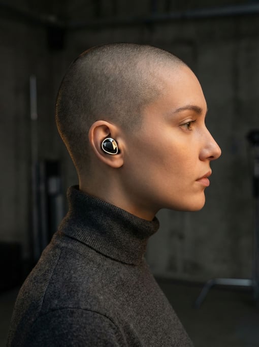 A person in profile wearing concept translation earbuds