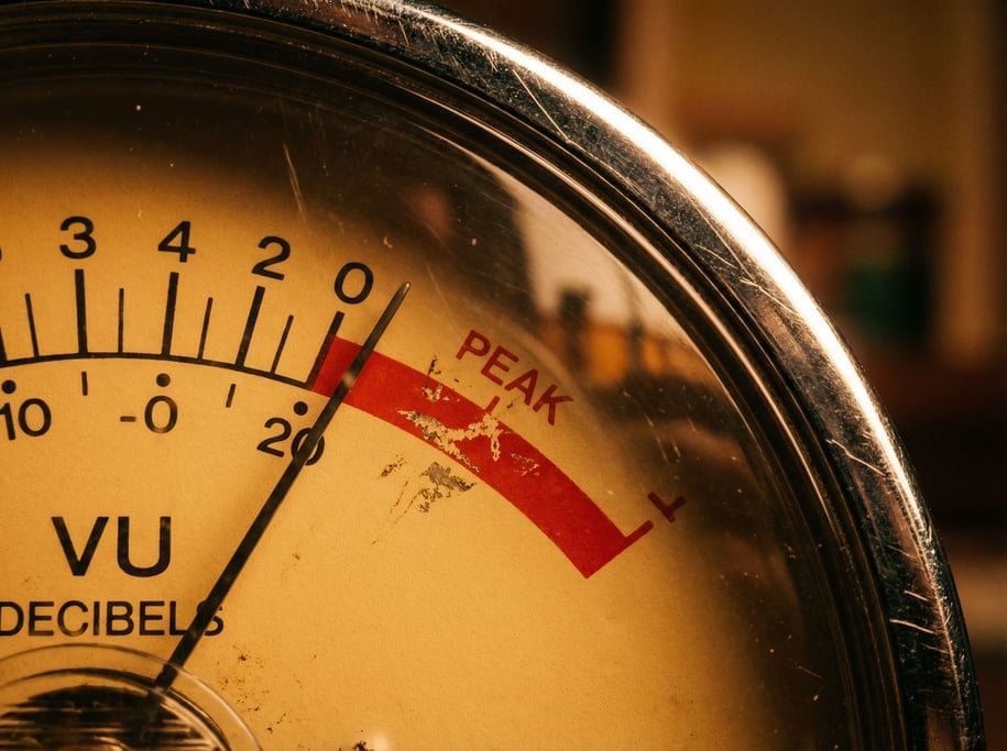 The amber face of a vintage VU meter fills the frame at extreme macro distance