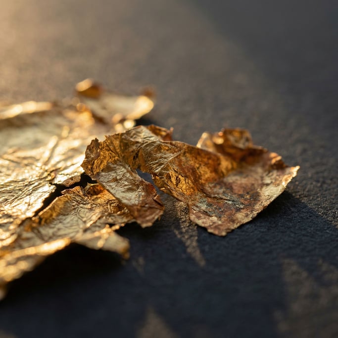 Extreme close-up of Crumpled gold leaf on a matte dark surface, fragile and luminous (xuc68uo5)